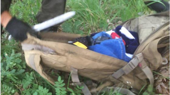 Ein Menschenjäger durchwühlt einen Rucksack, den offenbar ein Flüchtling zurück gelassen hat