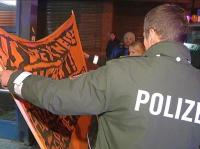 Ein Polizist stellt ein Plakat der Demonstranten sicher. Foto: videonews24.de