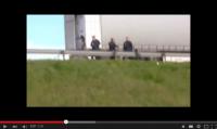 Calais: Ein CRS-Polizist schubst eine Person gewaltvoll über die Leitplanke.