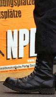 Mann mit Springerstiefeln vor einem NPD-Wahlplakat