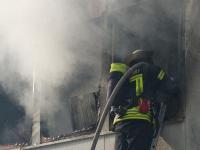 Ein Feuerwehrmann mit Atemschutzausrüstung bekämpft die Flammen im Inneren des Flüchtlingswohnheims.
