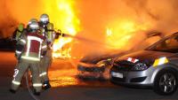Feuerwehrmänner löschen die lichterloh brennenden Autos