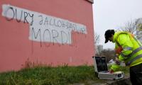Ein Kriminaltechniker sichert in Halle-Neustadt Spuren vor einer Wand mit dem Schriftzug «Oury Jalloh - Das war Mord»
