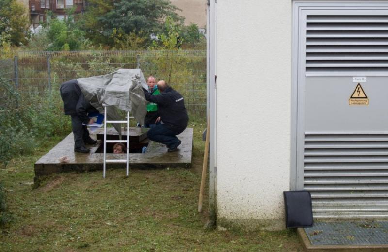 Nachforschungen nach dem Brandsatz-Fund: Kriminaltechniker untersuchen einen Kabelschacht Foto: DPA