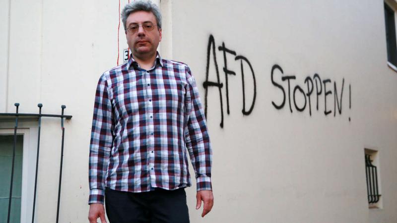  AfD Politiker Alexander Tassis vor der beschmierten Hauswand