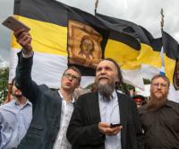 Foto: Alexander Dugin (Mitte) und Mitstreiter Valeri Korovin (rechts). Dahinter eine Variante der schwarz-gelb-weißen Flagge des russischen Imperiums. In den Händen: westliche Smartphones.