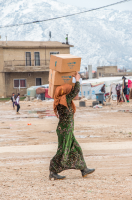 Eine Frau trägt die gerade bekommenen UNICEF-Hilfsgüter (Winterklamotten für Kinder) ins Camp.