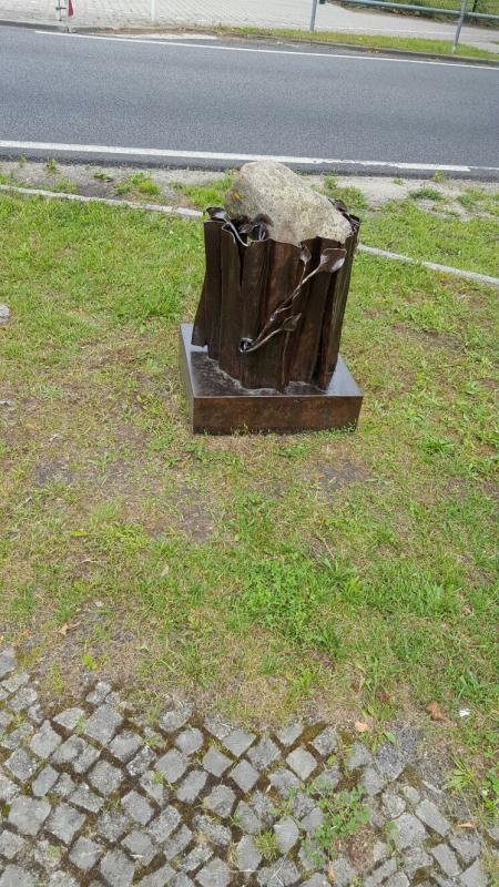 Das Denkmal. Ein Feldstein in einem eisernen Baumstumpf. Daneben: Gedenkbuch aus Metall