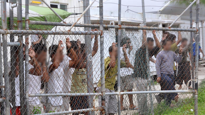 Asylum seekers stand behind a fence in Oscar compound at the Manus Island detention centre in Papua New Guinea, (AAP ImageEoin Blackwell) (Source AAP)