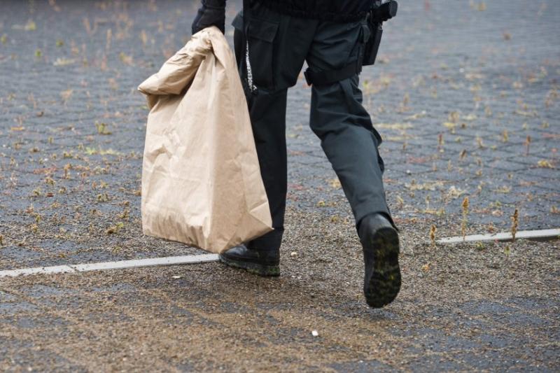 Ermittlungen: Ein LKA-Mitarbeiter trägt einen Papiersack vom Ort, wo die Brandsätze gefunden wurden Foto: DPA