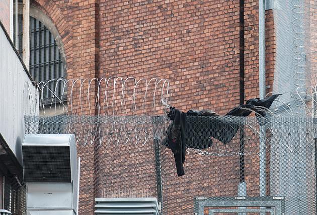 Jacke in Stacheldraht auf Knastmauer